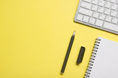 Laptop, akıllı telefon ve bir fincan kahveli diğer iş gereçleri olan sarı masa ofisi. Metni kopyalamak için üst görünümü kullan. Desenci çalışma alanı düz masa üzerinde temel elementler yatıyordu