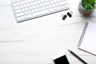 Bilgisayarlı beyaz masa ofisi, akıllı telefon ve bir fincan kahveli diğer iş malzemeleri. Metni kopyalamak için üst görünümü kullan. Desenci çalışma alanı düz masa üzerinde temel elementler yatıyordu