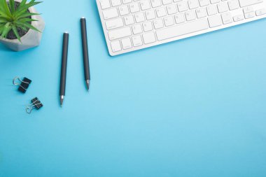 Dizüstü bilgisayarı, akıllı telefonu ve bir fincan kahveli diğer iş malzemeleri olan mavi masa ofisi. Metni kopyalamak için üst görünümü kullan. Desenci çalışma alanı düz masa üzerinde temel elementler yatıyordu