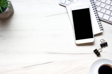Bilgisayarlı beyaz masa ofisi, akıllı telefon ve bir fincan kahveli diğer iş malzemeleri. Metni kopyalamak için üst görünümü kullan. Desenci çalışma alanı düz masa üzerinde temel elementler yatıyordu