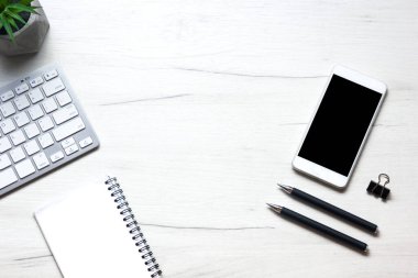 Bilgisayarlı beyaz masa ofisi, akıllı telefon ve bir fincan kahveli diğer iş malzemeleri. Metni kopyalamak için üst görünümü kullan. Desenci çalışma alanı düz masa üzerinde temel elementler yatıyordu