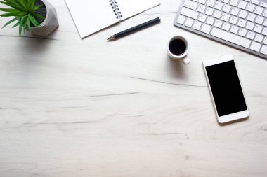 Bilgisayarlı beyaz masa ofisi, akıllı telefon ve bir fincan kahveli diğer iş malzemeleri. Metni kopyalamak için üst görünümü kullan. Desenci çalışma alanı düz masa üzerinde temel elementler yatıyordu