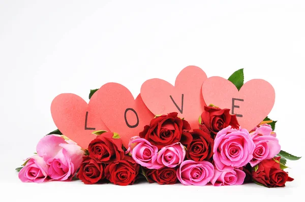 Rosas vermelhas e rosa com cartão de Valentim em forma de coração — Fotografia de Stock