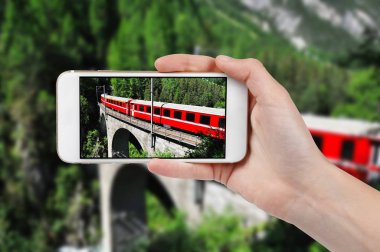 Fotoğrafta kırmızı tren bir telefonla Viyadüğü üzerinde