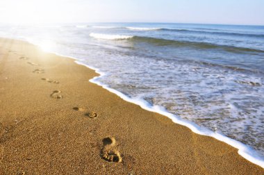 Footprints on the beach in sunset clipart