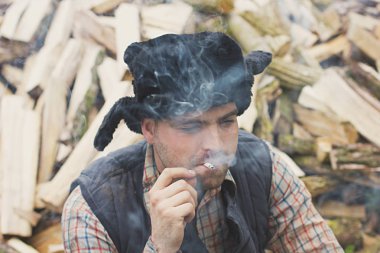 Oduncu balta yakacak odun arka planı ile şapkalı