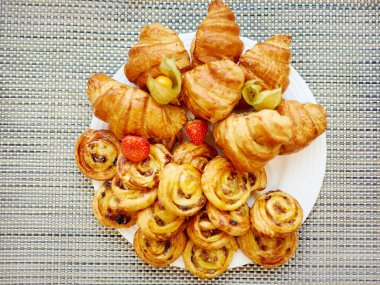 Roissantlar ve diğer tatlılar beyaz tabaklarda yatıyor.