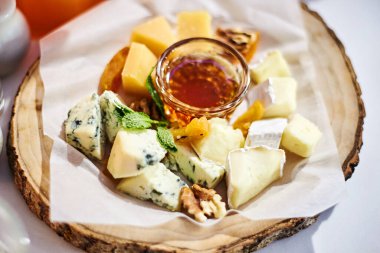 Soslu bir tabakta değişik çeşitte peynir parçaları var.