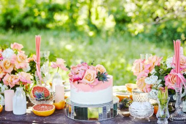 Düğün dekoru pasta, mum ve meyvelerle dolu bir masada.