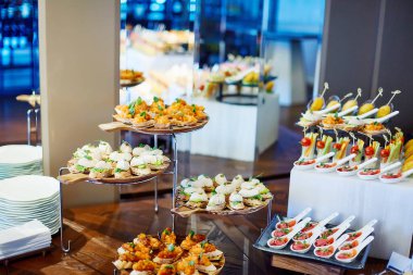 Konserve ahşap büfe masası ve arka planda aynalar ile tepsilerde duran çeşitli kanepeler.