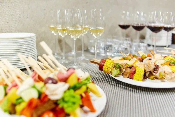 白ワインと赤ワインのグラスの近くの白いプレートに横たわっている野菜のケバブとプレートのスタック — ストック写真