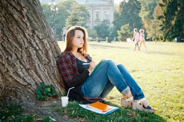 Ağacın yanındaki kız öğrenci dersin ve hayallerin başlamasını bekliyor.