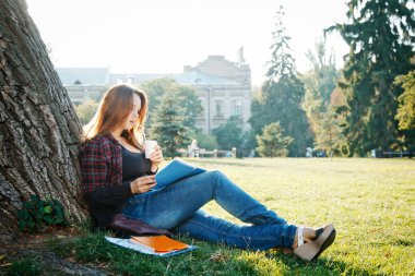 Ağacın yanındaki kız öğrenci dersin ve hayallerin başlamasını bekliyor.