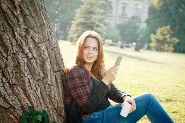 Ağacın yanındaki kız öğrenci dersin ve hayallerin başlamasını bekliyor.