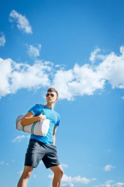 Genç ve neşeli sporcu güneşin altında gökyüzüne karşı
