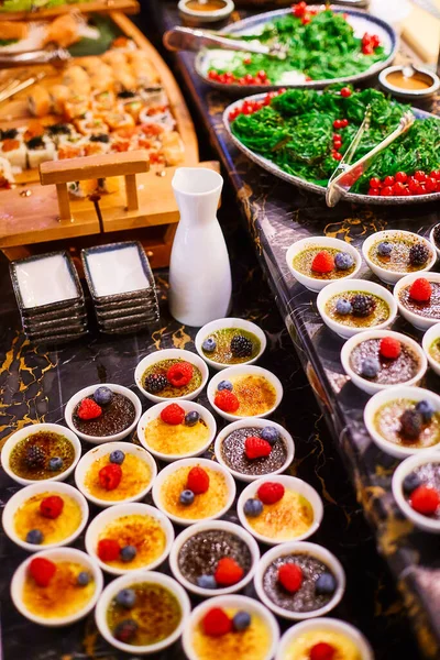 A buffet table on which there are two types of souffl in white bowls decorated with raspberries