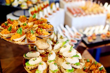 Tahta tepsilerde çeşitli kanepeleri olan konserve büfe masası. 