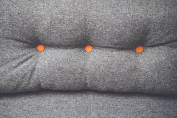 つの丸いオレンジ色のボタンはソファとクローズ アップ グレー色の枕 — ストック写真