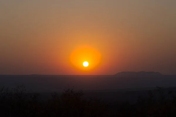 Czerwony zachód słońca nad dużym obszarem ze wzgórzami — Zdjęcie stockowe