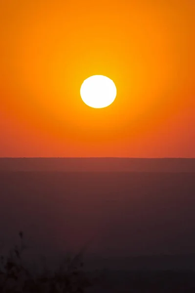 Grande pôr-do-sol vermelho sobre silhuetas de colinas — Fotografia de Stock