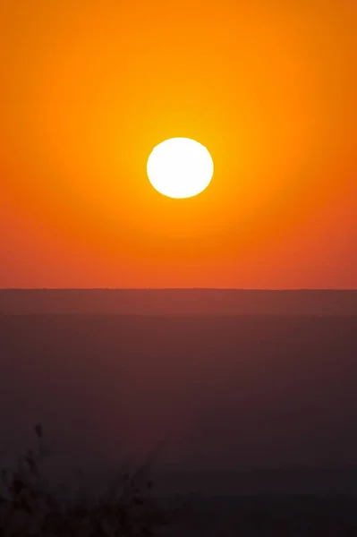 Duży czerwony zachód słońca nad sylwetkami wzgórz — Zdjęcie stockowe