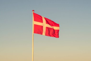 Şafakta Danimarka bayrağı Güneşli bir akşamda rüzgarda sallanıyor.