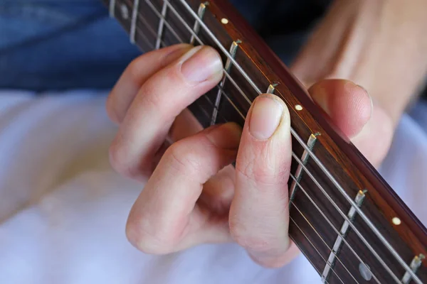 Musician's hand forming chord on electric guitar