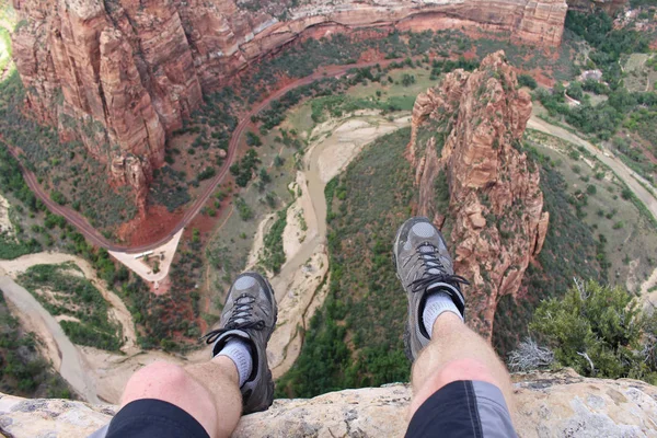 Eerste persoon perspectief shot van een wandelaar zittend aan de rand van een klif aan Angel's Landing in Zion Nationaal Park. — Stockfoto