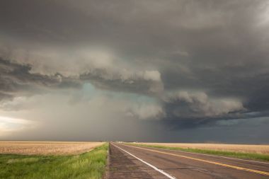 A powerful supercell thunderstorm looms over the highway. clipart