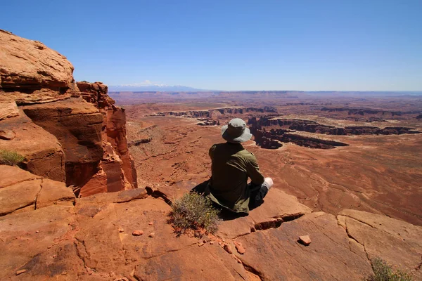 A hiker sits at the edge of a cliff in Utah's Canyonlands National Park. — Stock Photo, Image