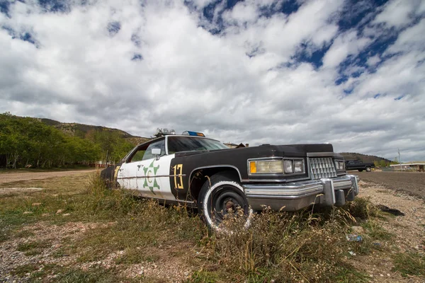 A broken down police car in an overgrown gravel lot. — Stock Photo, Image