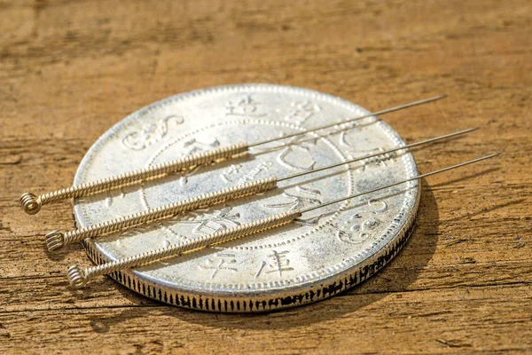 Иглы для иглоукалывания на китайской монете — стоковое фото