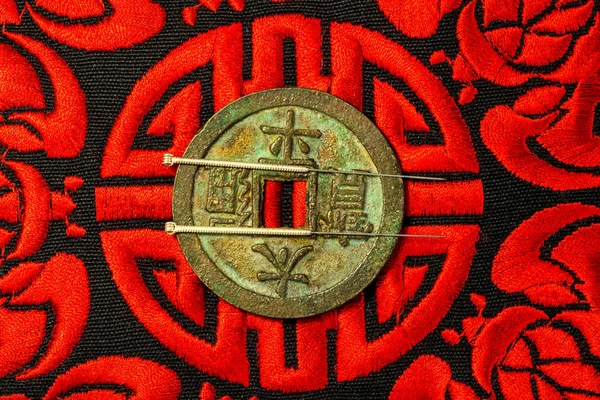 Acupuncture needles on Chinese coin and symbol for immortality — Stock Photo, Image