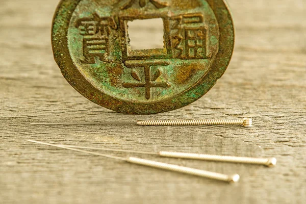 Acupuncture needles on antique Chinese coin — Stock Photo, Image