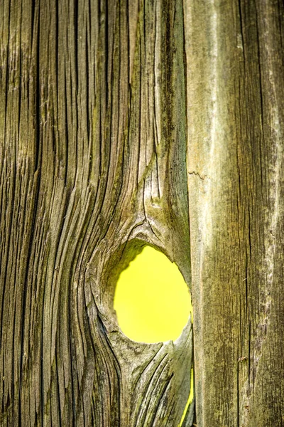 Old plank with hole and view to a yellow background — Stock Photo, Image