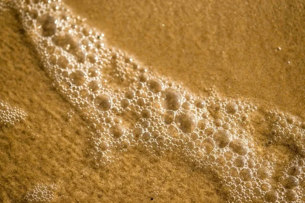 Sandstrand med skum av surf — Stockfoto