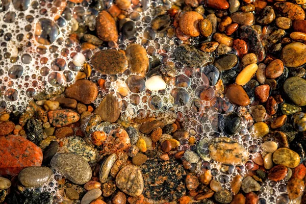 หาดทรายที่มีก้อนหินและสเปรย์ของกระดานโต้คลื่น — ภาพถ่ายสต็อก