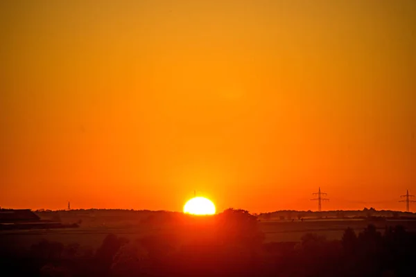 Puesta de sol con resplandor posterior y mástil de potencia — Foto de Stock