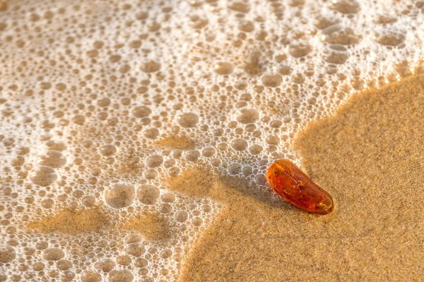 Amber op een strand van de Oostzee in de branding — Stockfoto