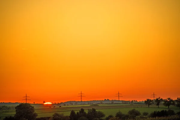 Puesta de sol en otoño con mástiles de potencia — Foto de Stock