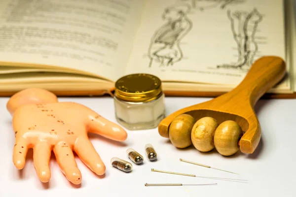 Agujas de acupuntura con modelo de mano, rodillo de masaje, pastillas, pomada y libro de texto —  Fotos de Stock