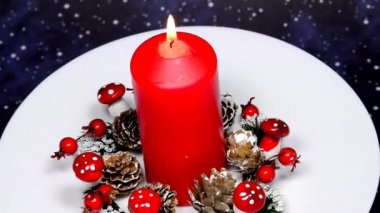 Gelen çelenk ve yanan mumla Noel süslemesi