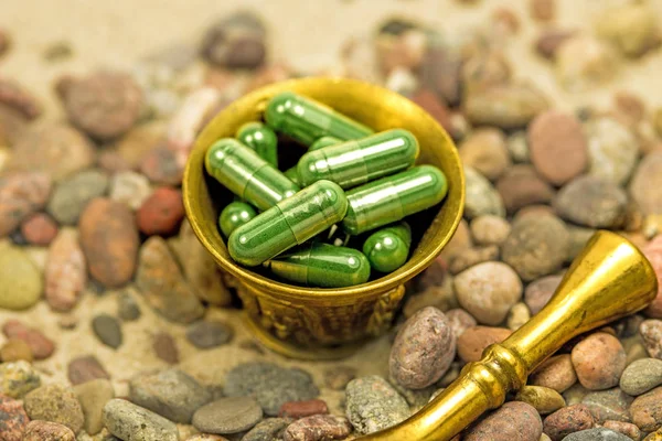 Spirulina capsules in een mortel op een strand met kiezelstenen — Stockfoto