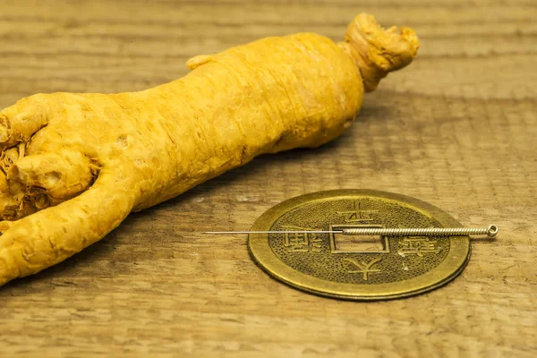 Acupuncture needle on Chinese coin with ginseng root — 图库照片