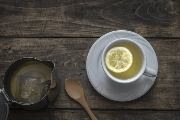 Чашка чая с лимоном на деревянном столе — стоковое фото