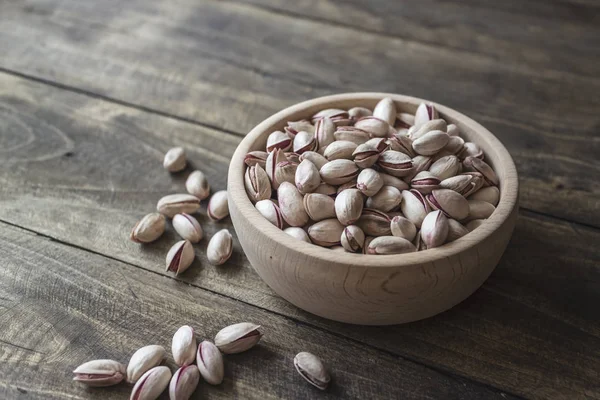 Small bowl of pistachios on wooden table — Stock Photo, Image