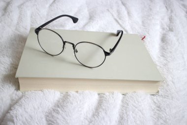 kitap ve bir yatakta gözlük