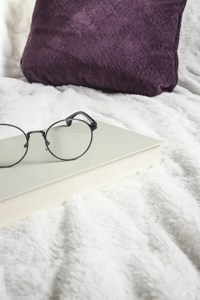 Книга и очки на кровати — стоковое фото
