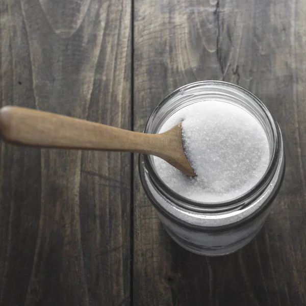 Azúcar en cuchara de madera y frasco de vidrio — Foto de Stock