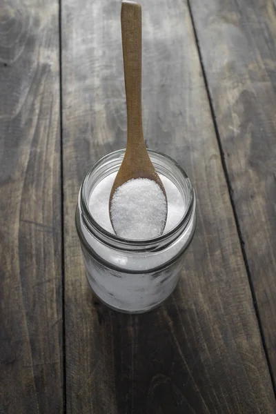 Sugar in wooden spoon and glass jar — Stock Photo, Image